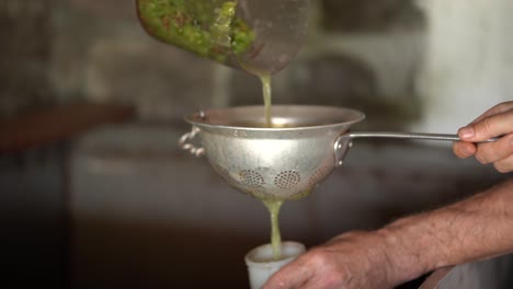 Pouring-freshly-crushed-grape-juice-into-a-testing-jar-through-an-old-aluminium-sieve