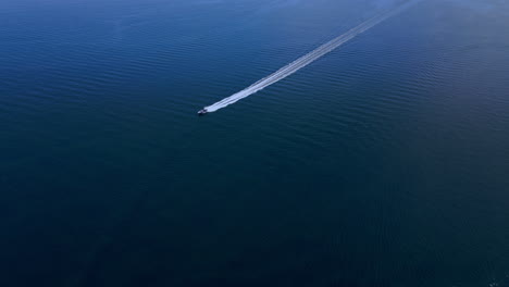 Boat-speeding-through-the-blue-waters-of-Långedrag,-Gothenburg,-Sweden---aerial
