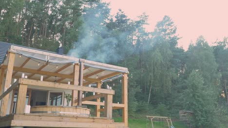 White-Smoke-Rising-From-A-Chimney-Of-A-Wooden-Hot-Tub-Outside-Cabin-By-The-Lush-Forest-In-Poland