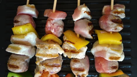Close-up-of-four-tasty-skewers-on-grill,-chicken,-sausage-and-pepper,-slider