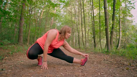 Caucasian-women-in-sportswear-stretching-legs-and-exercising-in-the-forest-trail