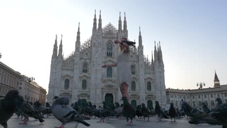 Blonde-Female-model-in-front-of-the-Milan-Cathedral-Duomo-playing-with-pigeons-on-a-summer-morning-day-in-Milan,-Italy