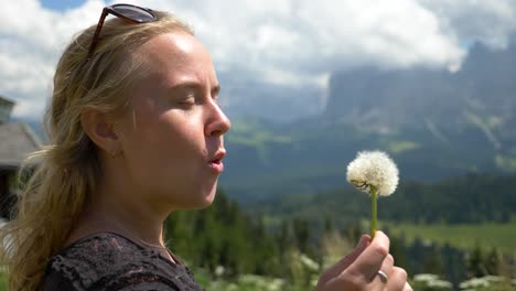 Super-slow-Mo-of-a-Caucasian-female-model-blowing-a-dandelion-flower-in-against-the-wind,-Seiser-Alm,-Val-Gardena,-South-Tirol