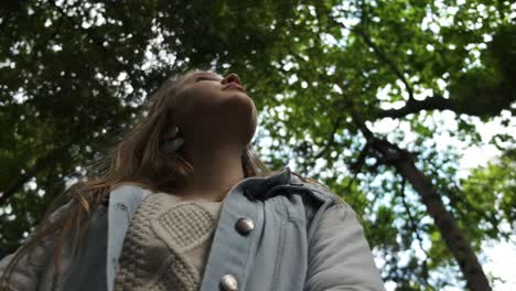 Young-Caucasian-female-looking-up-at-woodland-tree-canopy-imagination-expression-concept