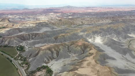 Aerial-View-of-Utah-Desert-National-Park,-Road-Behind-Desert-Landscape-Sandstone-Hills-in-Wayne-County-Near-Factory-Butte