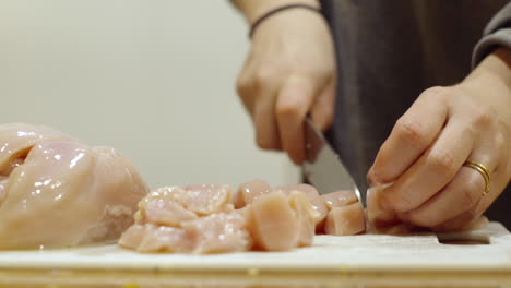 Close-up-slicing-raw-chicken-with-a-knife-in-the-kitchen-for-dinner