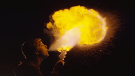 Feuershow-Künstler-Bläst-Goldenen-Feuerball-In-Dunkler,-Superlangsamer-Bewegung