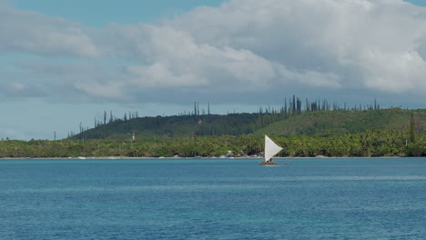 Piragua-Canaca-Hecha-A-Mano-Con-Flotadores-De-Vela-Triangular-En-La-Bahía-De-Upi,-Cerca-De-La-Isla-De-Los-Pinos