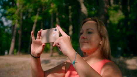 Caucasian-woman-holding-a-mobile-smartphone-taking-a-photo-in-the-forest