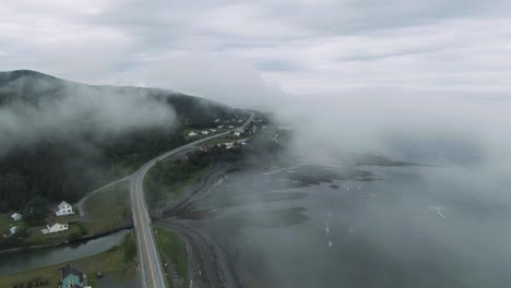 Clouds-Above-Chic-Choc-Mountains,-Village-Along-The-Road-At-Gaspe-Peninsula,-And-The-Saint-Lawrence-River-During-Misty-Morning-In-Quebec,-Canada