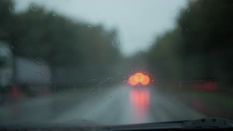 View-of-the-road-through-wet-car-window-in-rain-in-the-evening