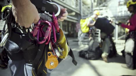 A-climbing-crew-adjusts-their-harnesses-and-safety-gear-before-climbing-an-industrial-building