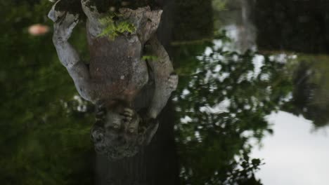 Tilt-up-across-classical-stone-statue-and-reflection-in-slow-motion-calming-fountain-water