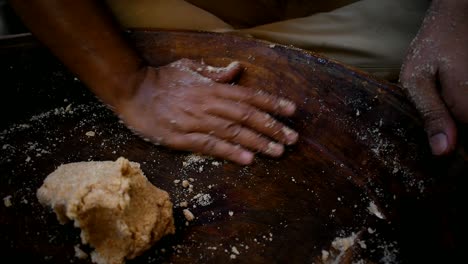 close-up-of-a-mans-hand-kneading-flourcdough-in-a-old-wooden-plate