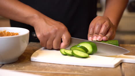 Hands-slicing-zucchini-to-eat-with-a-freshly-made-dip-as-a-healthy-snack---isolated-frontal-view