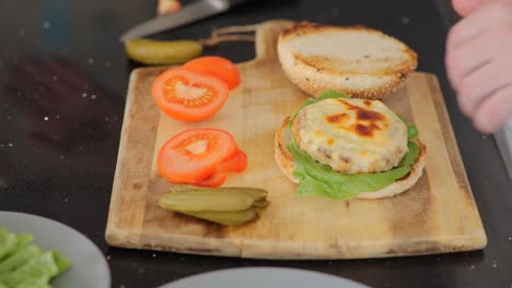 Close-up-of-assembling-a-freshly-grilled-chicken-burger-with-mayo-and-pickles