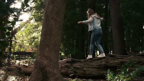 Balancierende-Fähigkeiten-Des-Jungen-Mädchens-Auf-Einem-Großen-Umgestürzten-Baumstamm-In-Der-Waldwildnis