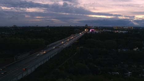 Morning-traffic-on-A40-highway-at-dawn,-aerial-view-with-Dortmund-City-skyline
