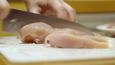 Close-up-cutting-raw-chicken-with-a-knife-in-the-kitchen