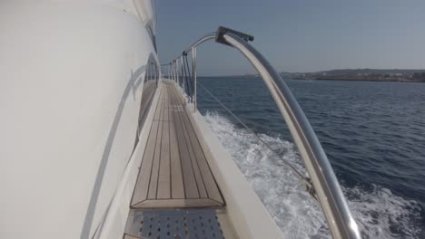 View-down-the-side-of-a-yacht-of-the-narrow-path-on-deck-and-the-wake-of-the-boat-as-it-speeds-through-the-water