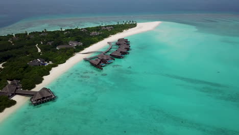 Wide-lowering-drone-shot-of-private-villas-over-the-turquoise-water