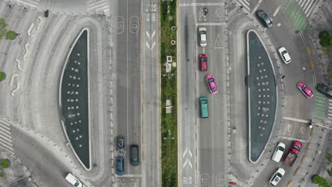 Aerial-birds-eye-view-of-a-roundabout-with-cars,-bicycles,-buses-and-people-walking-by