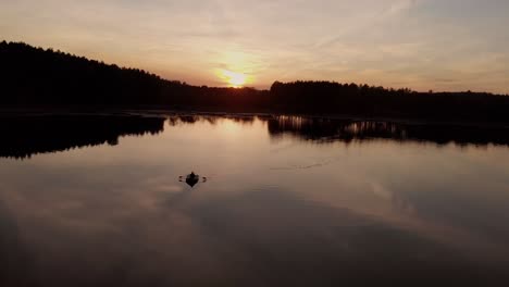 Silhouettenreflexion-Mit-Einem-Mann,-Der-Während-Des-Sonnenuntergangs-In-Einem-Ruhigen-Wasser-Eines-Sees-In-Rogowko,-Polen,-Paddelt