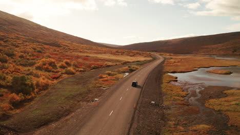 Traveling-on-the-road-through-the-autumn-red-landscape-of-East-Iceland--aerial