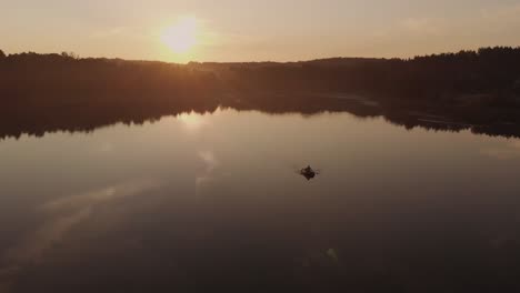 Lone-Man-Paddling-A-Boat-In-The-Middle-Of-A-Quiet-Lake-In-The-Village-Near-Rogowko,-Poland-Through-Golden-Hour