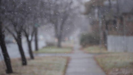 Nieve-Cayendo-En-La-Acera-Del-Vecindario-En-El-Frío-Día-De-Invierno,-Fuera-De-Foco-En-La-Nieve