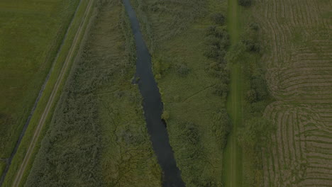 Drohne,-Die-Einem-Kleinen-Lokalen-Fluss-Folgt-Und-Wunderschöne-Grüne-Feldlandschaften-Im-Dorf-Debki-In-Nordpolen-Enthüllt,-Kippe-Nach-Oben