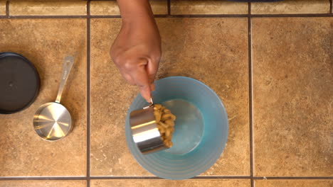 Measuring-cashews-and-pouring-them-in-a-bowl-for-a-homemade-nutty-recipe--overhead-view
