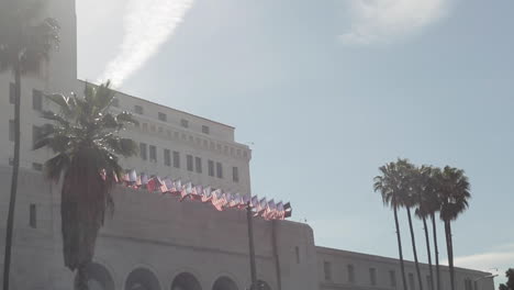 Sunny-Bright-Day-With-Palm-Trees,-Building,-American-Flags