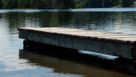 Low-Angle-Vacant-Wooden-Dock-Over-Rippling-Lake-Water