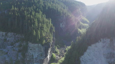 Aerial-view-of-ravine-in-rugged-Pacific-Northwest-mountains-with-sun-flare