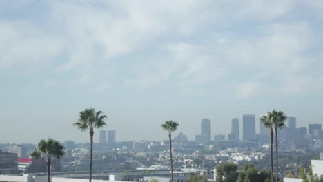 Palm-Trees-and-Los-Angeles-Skyline,-Downtown,-Cloudy-Blue-Sky