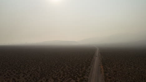 Descending-aerial-view-of-a-truck-and-cars-driving-through-the-Mojave-Desert-and-thick-smoke-caused-by-nearby-wildfires