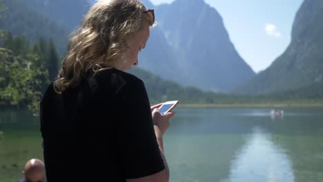 Blonde-Tourist-Lady-on-her-phone-while-on-vacation-in-a-beautiful-nature-setting