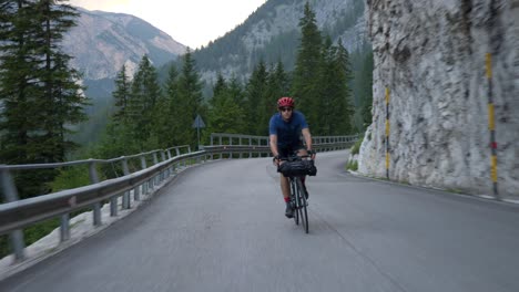 Man-on-a-racing-bike-cycling-down-hill-through-beautiful-nature-in-the-mountains,-Dolomiti,-Italy