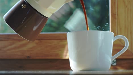 Person-Pouring-Hot-Coffee-Drink-Into-White-Cup-From-Moka-Pot