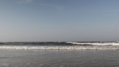 Low-angle-view-on-sea-waves-rolling-on-sandy-beach