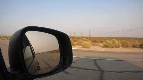 Driving-down-a-desert-highway-and-looking-at-the-side-view-mirror-as-another-car-approaches