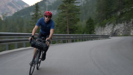 High-speed-chase,-healthy-man-on-a-bicycle-cycling-through-a-mountain-pass-in-the-Dolomites,-Italy