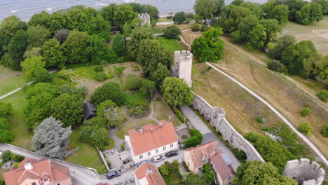 Aerial-view-of-medieval-city-wall-of-Visby-next-to-houses-and-green-trees