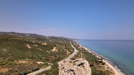 Clip-Aéreo-De-Drones-Que-Asciende-Sobre-Una-Antigua-Torre-En-Ruinas-Y-Una-Playa-En-Kavala,-Macedonia,-Grecia