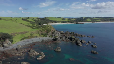El-Hermoso-Parque-Regional-De-La-Isla-De-Tawharanui-En-Nueva-Zelanda-Con-Un-Océano-Tranquilo-Y-Un-Cielo-Azul-Brillante-Arriba---Toma-Aérea