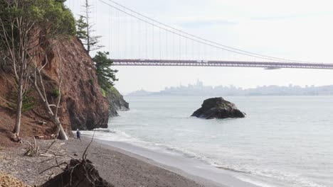 Niña-Caminando-Por-La-Orilla-Del-Mar-Con-San-Francisco-Y-El-Puente-Golden-Gate-En-El-Fondo