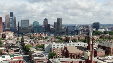 Aerial-parallax-shot-of-Baltimore,-Maryland,-USA-urban-city-neighborhood-community,-church-steeple,-United-States-USA-downtown-district-skyline,-Inner-Harbor-and-Chesapeake-Bay