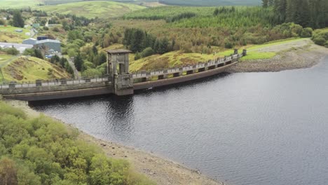 Alwen-reservoir-industrial-historical-rural-lake-dam-building-aerial-pull-away-countryside-reveal
