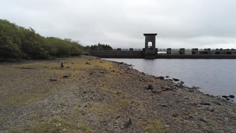 Alwen-reservoir-industrial-hydroelectric-landmark-historical-rural-lake-dam-building-pull-back-low-over-shoreline